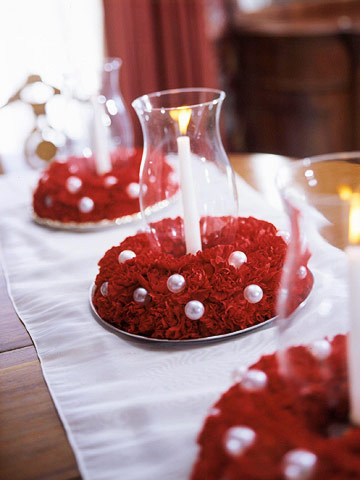 Red carnations and glass candle holdres centerpiece