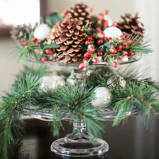 cake plates filled evergreens glass balls pinecones and red berries