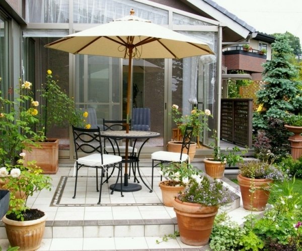 small terrace courtyard clay pots flowers wrought iron furniture