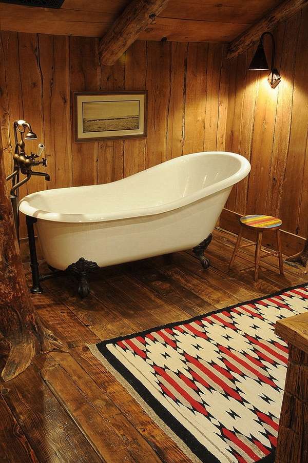Rustic bathroom white claw foot tub wood flooring area rug