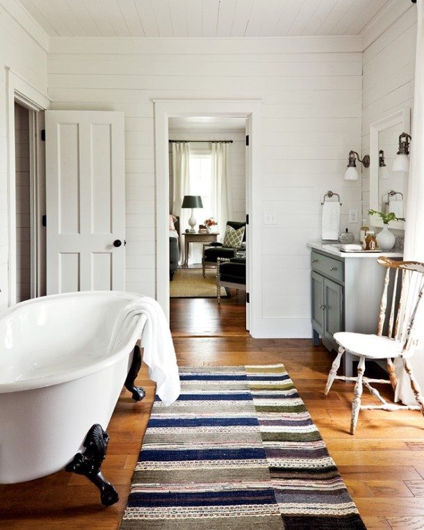 farmhouse bathroom interior wood flooring area rug clawfoot tub vintage vanity cabinet