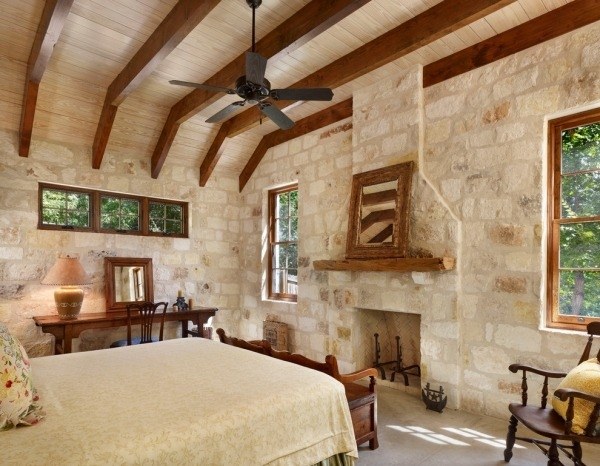 rustic bedroom exposed beams fireplace limestone flooring Tuscan-style decor