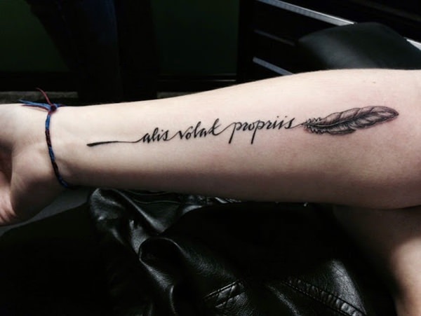 feather and inscription tatoo on forearm