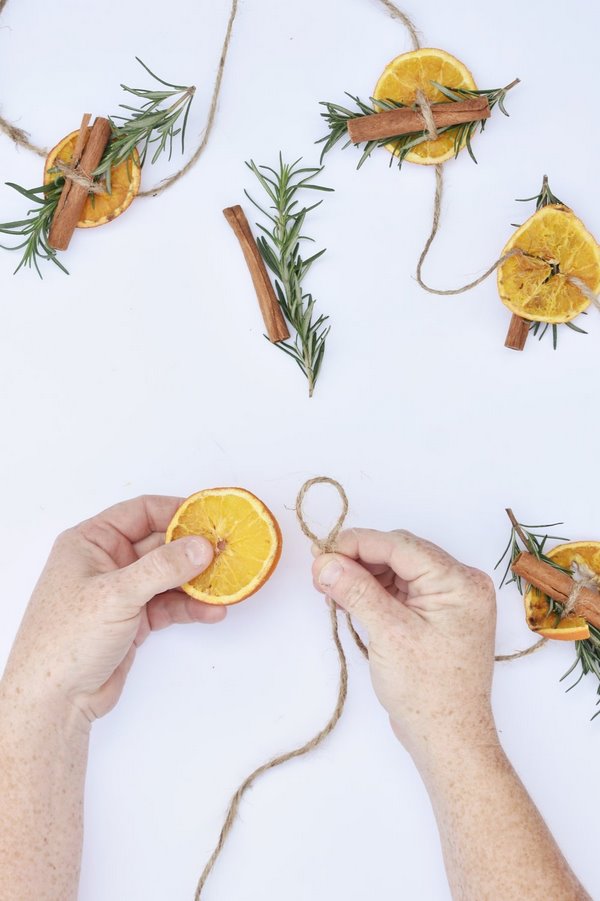 Homemade holiday decorations DIY orange garland with rosemary and cinnamon sticks
