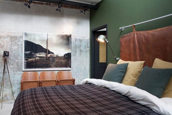 industrial style bedroom with a cool headboard and a green wall