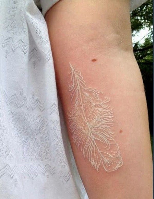 white ink feather tattoo on forearm