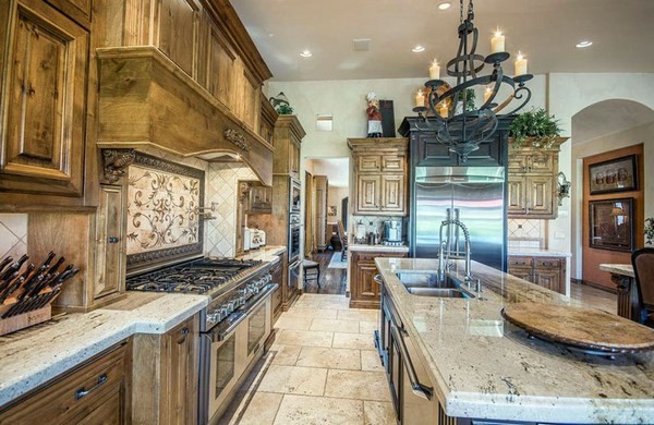 italian style kitchen with decorative backsplash and wrought iron chandeliers