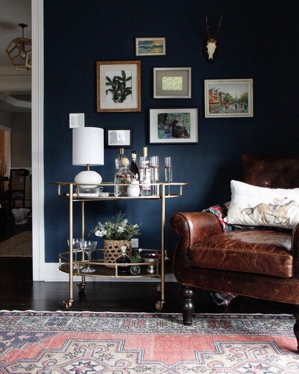 stylish living room design blue wall paint leather armchair brass bar cart