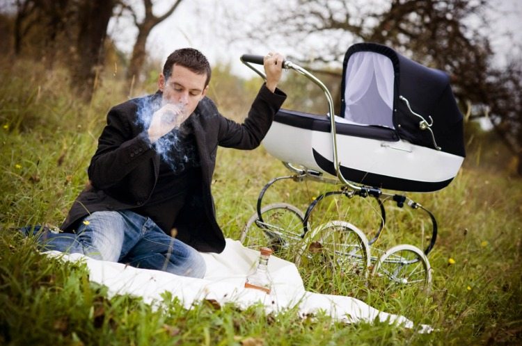 a young father smoking a cigar in park
