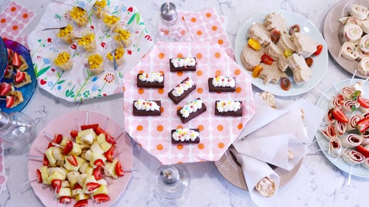 colorful sweet and savory party finger food snacks with fruits ham cheese rice chips and corn