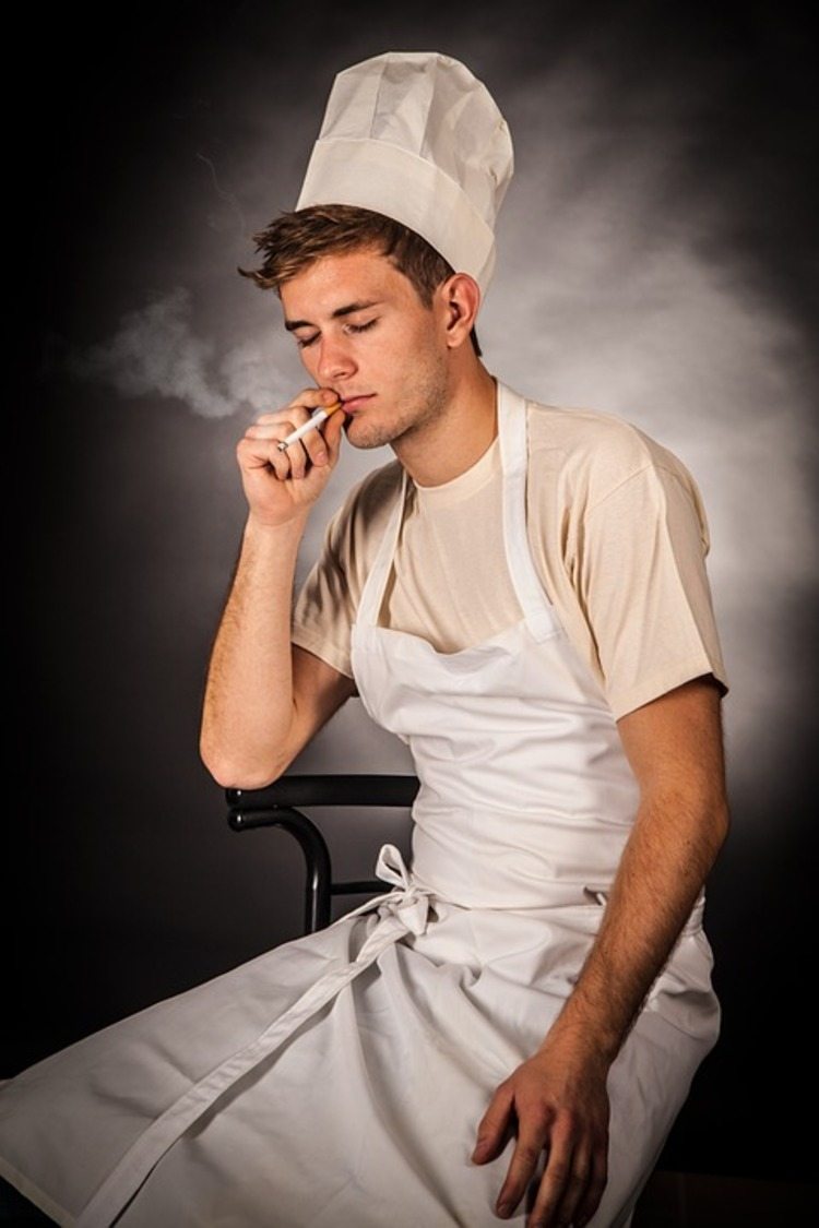 cook with hat and white apron smokes a cigarette