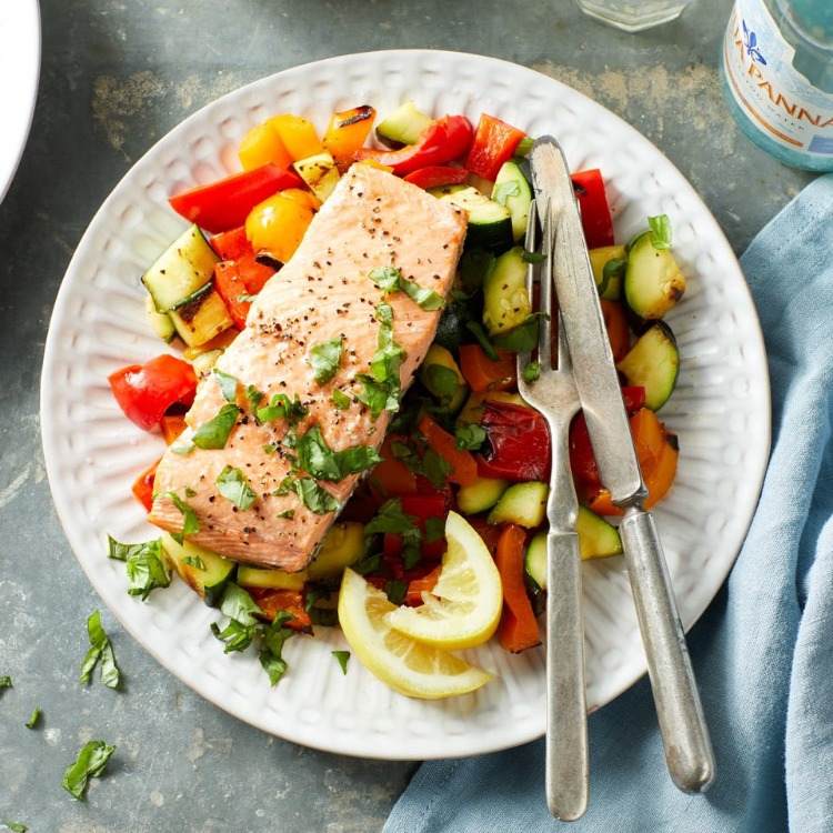 salmon with cooked vegetables in a dish with cutlery food for healthy teeth