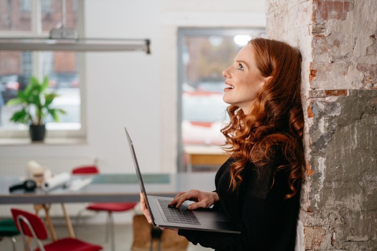 woman with beautiful curly red hair leaning on the wall in office 