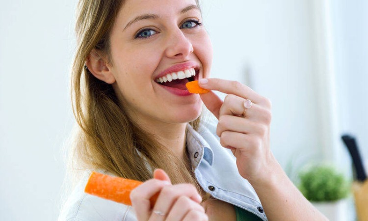 young woman eating carrot for healthy teeth 