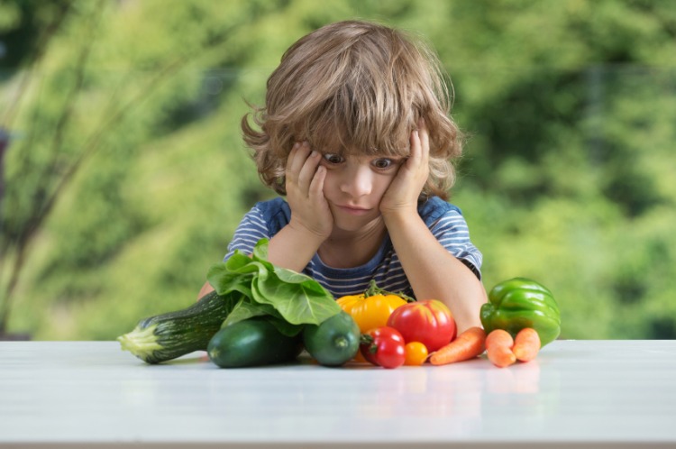a child looks at vegetables on the table