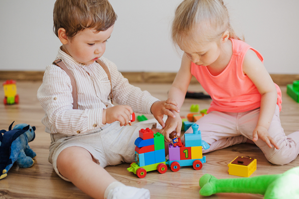 boy and girl playing with wooden toys on the floor