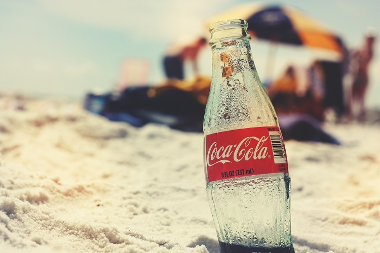 empty Coca Cola bottle in the sand