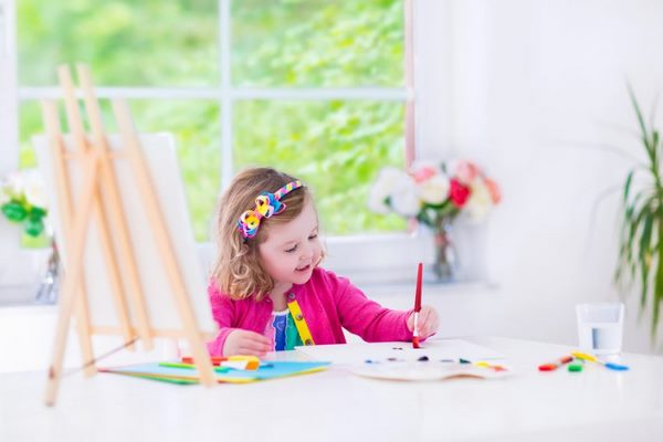 little girl drawing on a table