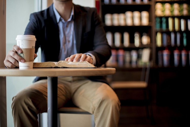 man sitting in cafe reading book