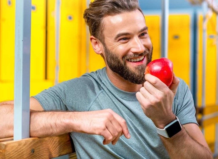 man with beard holding a red apple and smiling