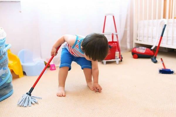 small boy cleaning the floor in his bedroom