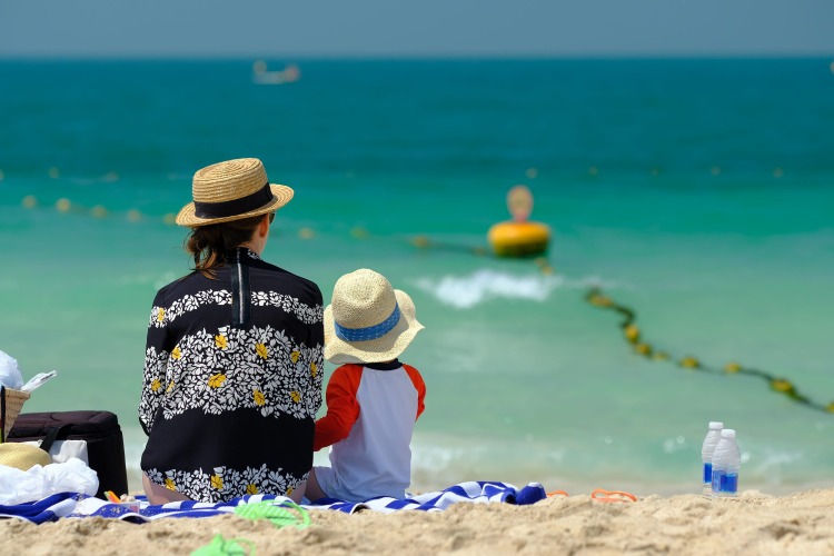 small boy with his mother at the beach with sun protection clothing