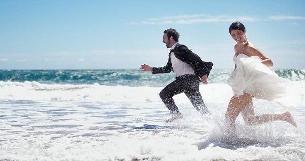 summer beach wedding bride and groom running having fun