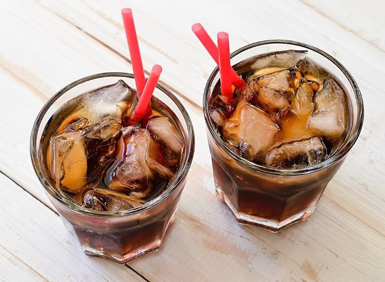 two glasses with carbonated drink and ice cubes 