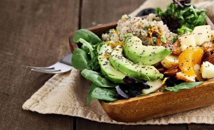 vegetarian dish with avocado quinoa apples in wooden bowl