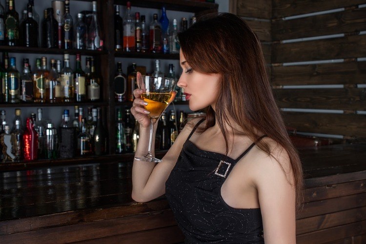 young woman in a bar holding a glass of wine