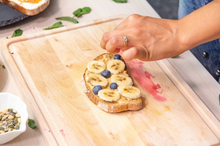 banana slices and blueberries on bread slice with peanut butter