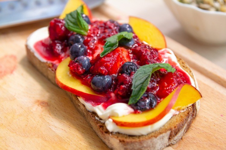 cream cheese on bread with peach slices berry and mint