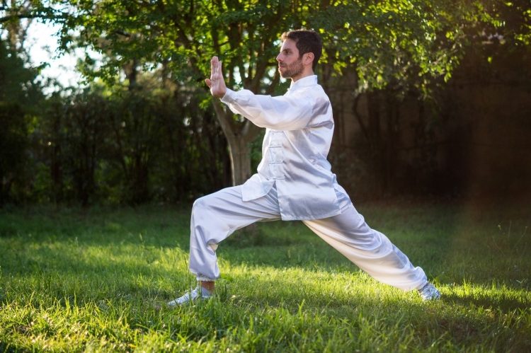 man in white clothing exercises tai chi Martial Art outdoors