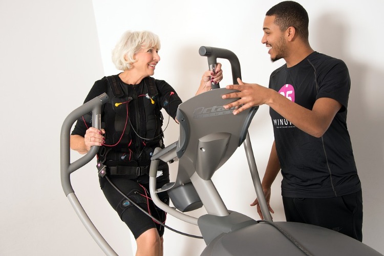 old woman with fitness instructor in cardio training with suit with sensors