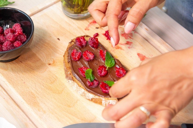 raspberries on bread slice with hazelnut cream and mint leaves