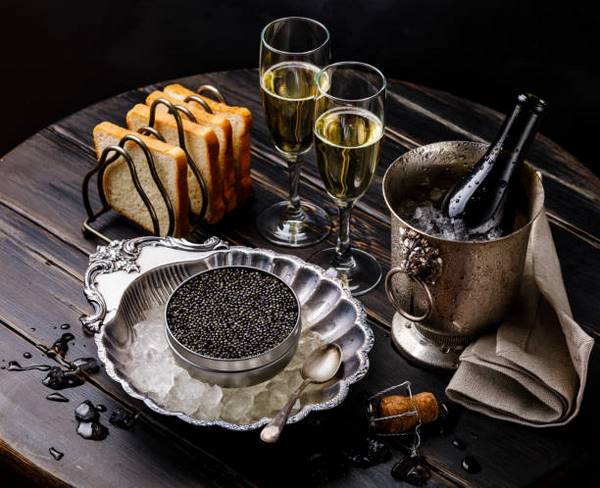 toasted bread bowl of caviar and glasses with champagne on table