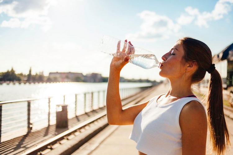 woman drinking water from plastic bottle 