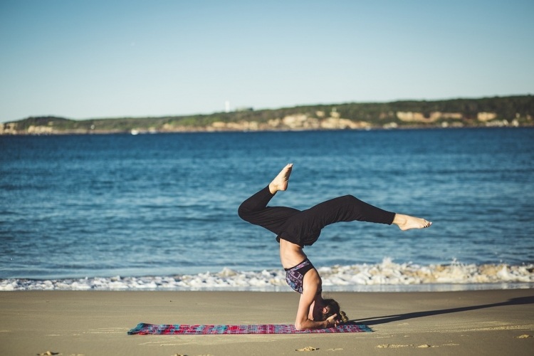 woman practicing yoga on beach