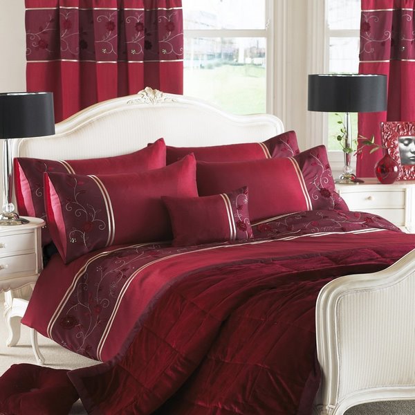 burgundy red bed sheets and curtains in white bedroom with black table lamps