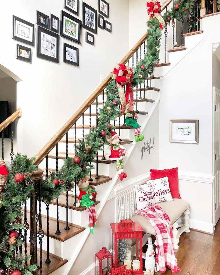 Christmas entryway garland on staircase bench with pillows and lantern