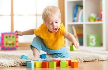 toddler-playing-with-cubes-on-the-floor-in-the-nursery-room