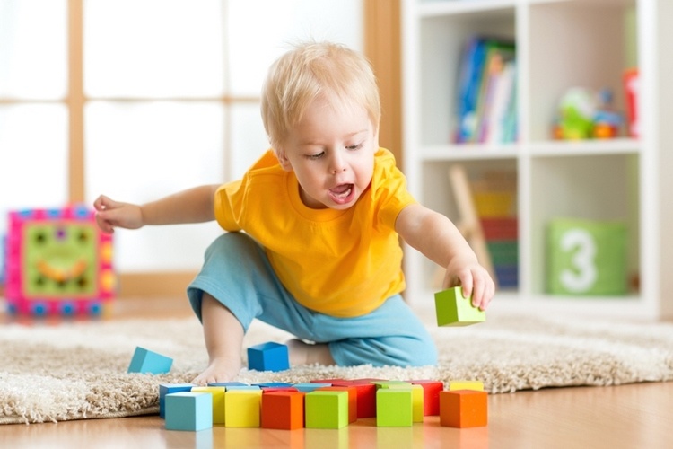 toddler playing with cubes on the floor in the nursery room