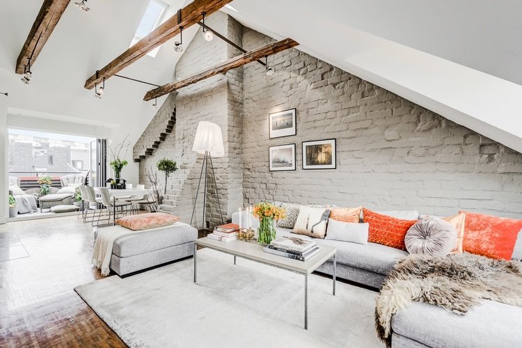 attic living room with whitewashed brick wall and exposed beams