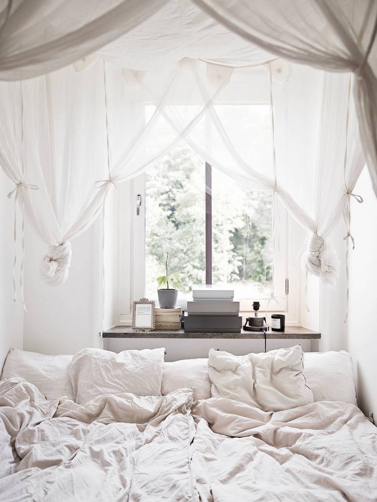 small bedroom with canopy bed in front the window