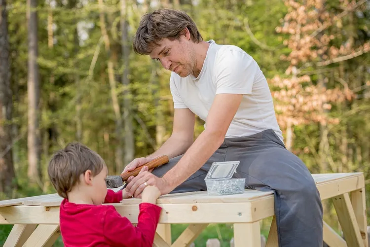 father and son building play house in the garden