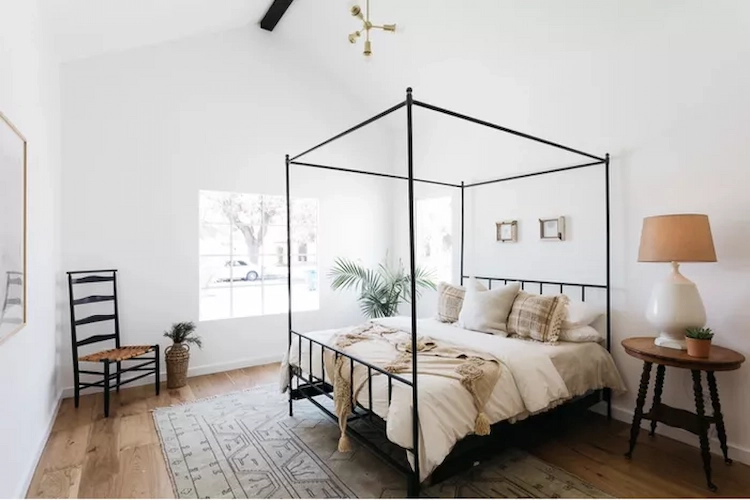 black canopy bed with thin frame contrasts with white walls in a modern bedroom