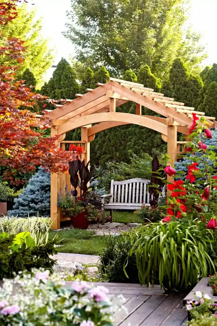 A wooden pergola among flowers and shrubs