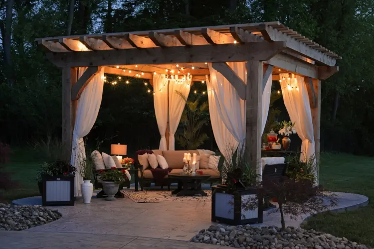 garden with a beautiful pergola with curtains and fairy lights