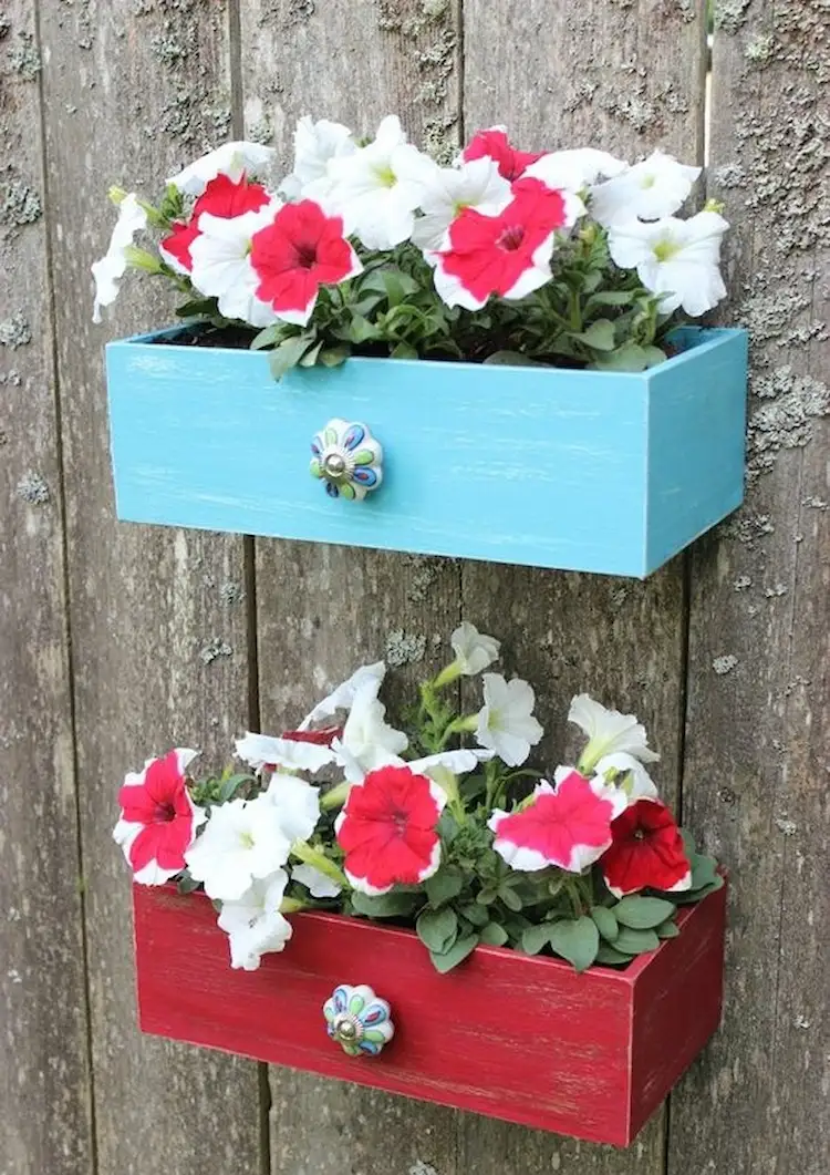 vertical flower boxes fixed to a wooden fence 