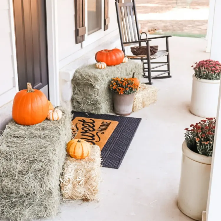 Front door design with bales of straw as a frame and pots with autumn flowers